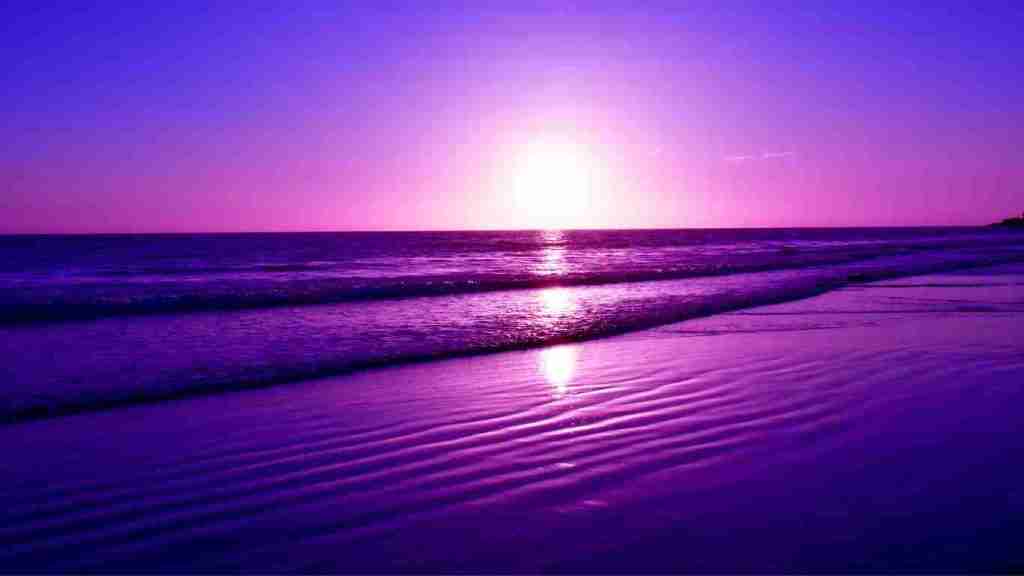 Calm sea and beach at sundown with a purple hue