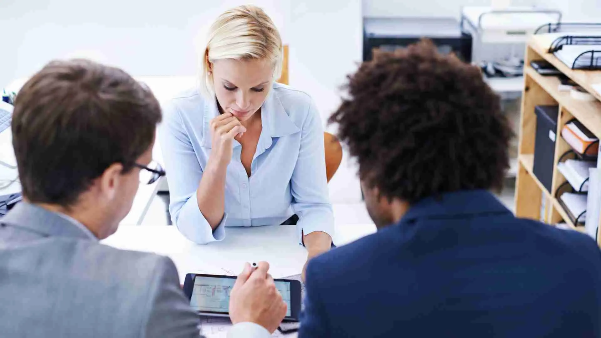 Leaders in meeting sitting around a table thinking about the decisions they need to make