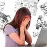 Female entrepreneur feeling entrepreneurial burnout in front of laptop with head in hands